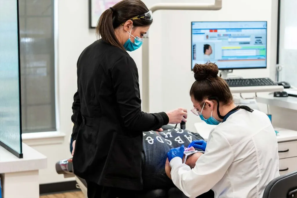 Two Dutchess Orthodontics clinicians treating a patient in the open-bay treatment area